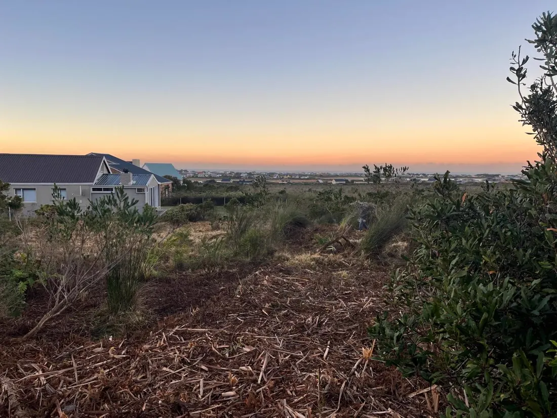 Cleared coastal plot beside a house at dusk